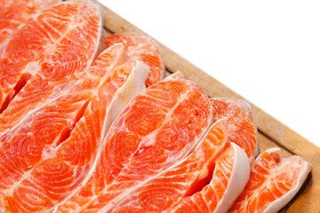 Cut in slices fresh raw salmon fillet steak on wooden board, isolated on white background, top view, copy space. Preparing salmon fillet for cooking