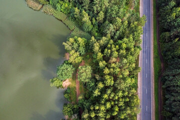 Aerial view of summer landscape with river and road across forest