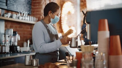 Beautiful Latin American Female Barista in Face Mask is Making a Cup of Cappuccino in Coffee Shop Bar. Social and Medical Health Restrictions Concept in a Loft-Style Cafe During Coronavirus Pandemic. - Powered by Adobe