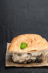 Homemade flaky pasty with chicken and mushroom filling on black stone table