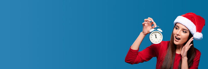 Celebration eve, excited joyful young woman wearing red santa hat holding clock and calls for sale,...
