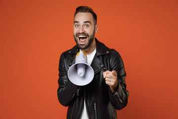 Excited young bearded man wearing casual basic white t-shirt, black leather jacket standing...