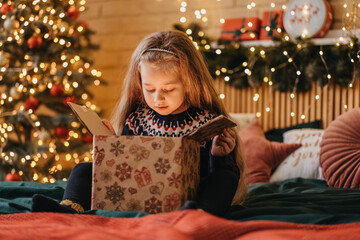 Excited girl opens gift box from Santa Claus, happy childhood, holiday celebration, Christmas miracle