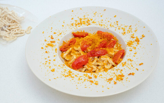 Fresh lorighittas semolina pasta with grated bottarga and cherry tomatoes
