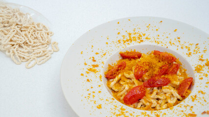 Fresh lorighittas semolina pasta with grated bottarga and cherry tomatoes