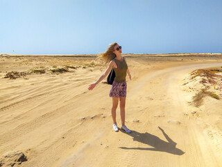 Girl tourist enjoying sun on windy day in desert on island Sal