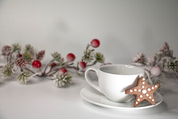 White cup with coffee, gingerbread cookies and christmas decorations on white background
