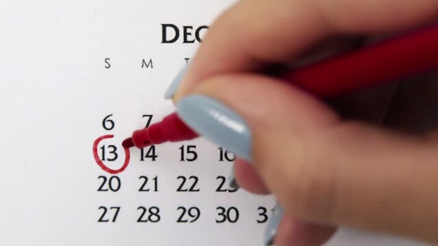 Female hand circle day in calendar date with a red marker. Business Basics Wall Calendar Planner and Organizer. December 13th
