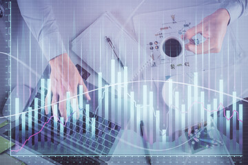 Multi exposure of man's hands typing over computer keyboard and forex graph hologram drawing. Top view. Financial markets concept.