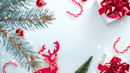 Noel background. White gift with scarlet bow, red balls and sparkling lights in xmas decoration on white background for greeting card. Christmas, winter, new year concept.