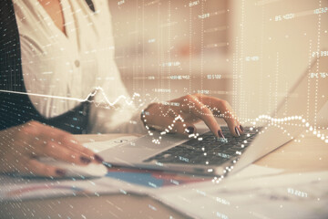 Double exposure of businesswoman hands typing on computer and forex graph hologram drawing. Financial analysis concept.