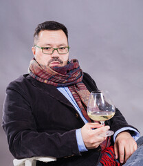 Solid cheerful man in kerchief sitting with glass of wine