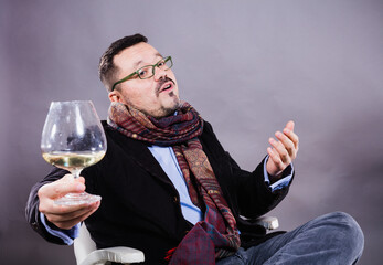 Solid cheerful man in kerchief sitting with glass of wine