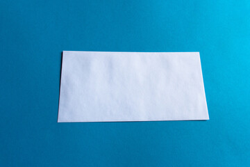 Front of a long, rectangular and plain white envelope on a plain blue background