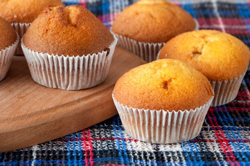 Close-up of freshly baked muffins. Delicious pastries are placed on a towel. Sweet dessert. Enjoy your meal.