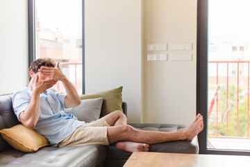 young man covering face with both hands saying no to the camera! refusing pictures or forbidding...