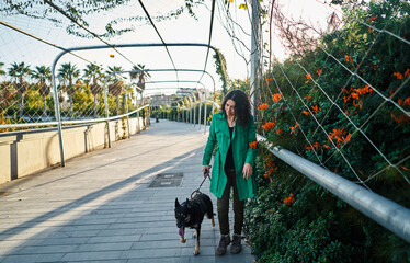 Young woman in green coat walks in the park with her dog at sunset. Friendship of the animal with...