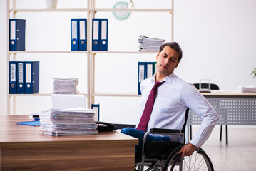 Young male employee after accident in wheel-chair at workplace