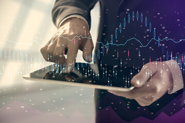 Fototapeta premium Double exposure of man's hands holding and using a digital device and forex graph drawing. Financial market concept.