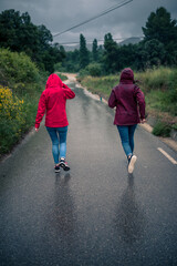 Fototapeta premium Girls in raincoat walking down a rain-wet road.