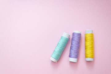 Colored sewing thread on a pink background