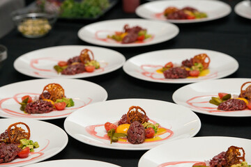 tartare meat with egg, cucumber, tomato and avocado closeup on a white plate.