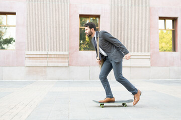 Side view of a man in his 30s wearing a suit and skating to his workplace