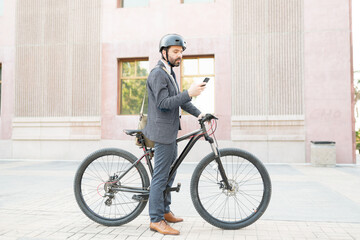 Side view of a businessman using his smartphone before starting to ride a bicycle