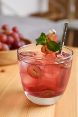 Refreshing drink with soda water, grapes, ice and mint on wooden table indoors