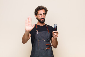 young man looking serious, stern, displeased and angry showing open palm making stop gesture