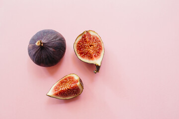 Fresh sliced and whole ripe figs on pink background. Food photo background. Flat lay, Top view. Copy space.