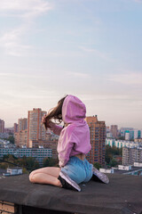 
girl in pink hoodie sitting on the roof