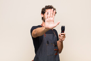 young man covering face with hand and putting other hand up front to stop camera, refusing photos...