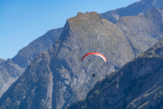 Paraplaners in tandem gliding in blue sky and Alpine mountains on paraplane