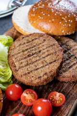 Fototapeta na wymiar Making tasty vegetarian hamburgers from plant based grilled burgers, fresh bakes buns and organic vegetables