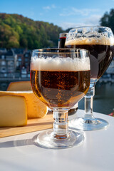 Drinking of dark and strong Belgian abbey beer with cheeses with nice view on Maas river and town Dinant, Belgium