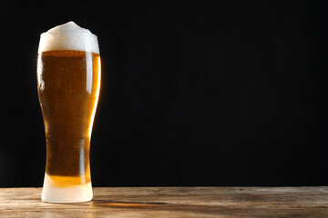 Cold tasty beer on wooden table against dark background. Space for text
