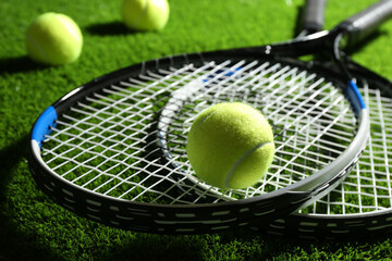 Tennis rackets and balls on green grass, closeup. Sports equipment