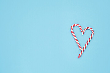 Heart made of candy canes on blue background. Minimal love concept. Space for text.