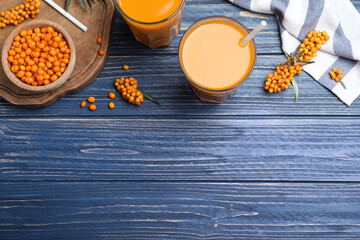 Flat lay composition with sea buckthorn juice on blue wooden table, space for text