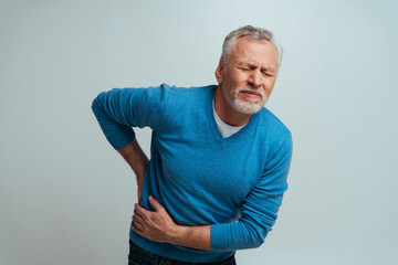 Handsome senior  isolated on grey background. Old man feeling pain. Concept about the third age and...