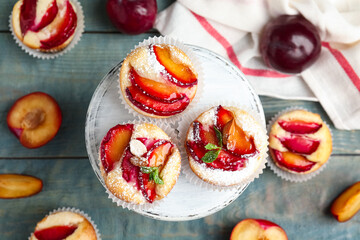 Delicious sweet cupcakes with plums on wooden stand, flat lay