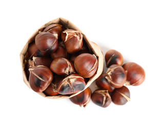 Paper bag with tasty roasted edible chestnuts on white background, top view