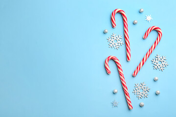 Candy canes and snowflakes on light blue background, flat lay with space for text. Christmas treat