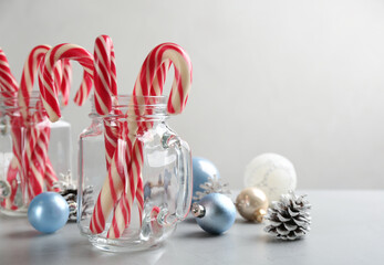 Candy canes and Christmas decor on light grey table, space for text
