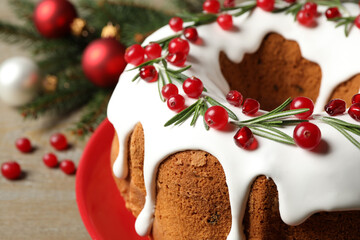 Traditional Christmas cake decorated with glaze, pomegranate seeds, cranberries and rosemary on table, closeup