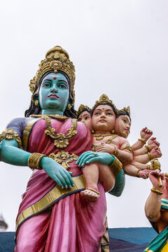 Kadirampura, Karnataka, India - November 4, 2013: Sri Murugan Temple. Closeup of colorful statue of parvati holding 6-headed baby Murugan under silver sky. 
