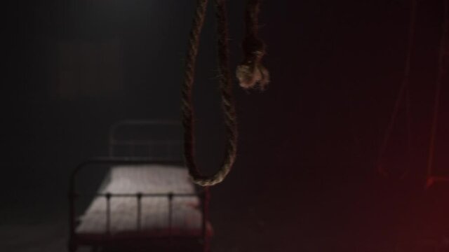 scary noose gallows for execution swings in dark against background of white metall bed in dark hospital or hangar sinister. Horror movie concept. bed with old mattress for corpse after hanging.