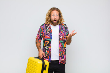 blonde man feeling extremely shocked and surprised, anxious and panicking, with a stressed and...