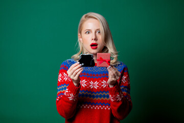 Beautiful woman in Christmas sweater with gift box and purse